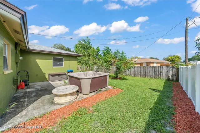 a view of a back yard of the house with a chairs and table in the patio