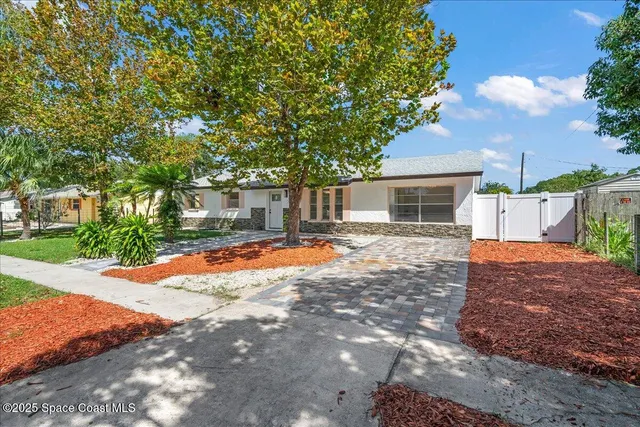 a backyard of a house with table and chairs under an umbrella