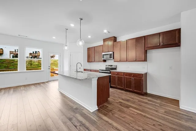 a large kitchen with stainless steel appliances wooden floors and wooden cabinets