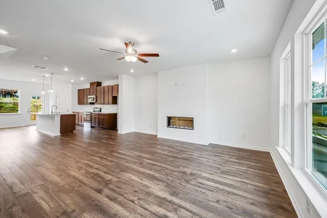 a view of an empty room with a window and wooden floor