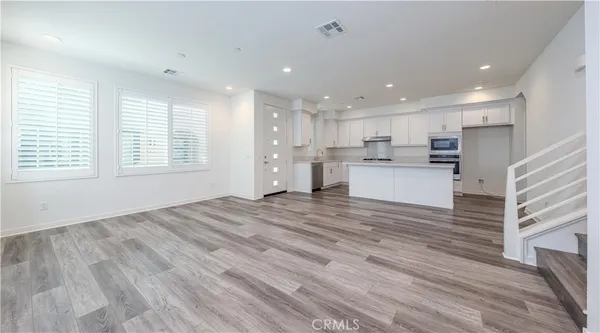 a open kitchen with kitchen island a stove a refrigerator cabinets and wooden floor