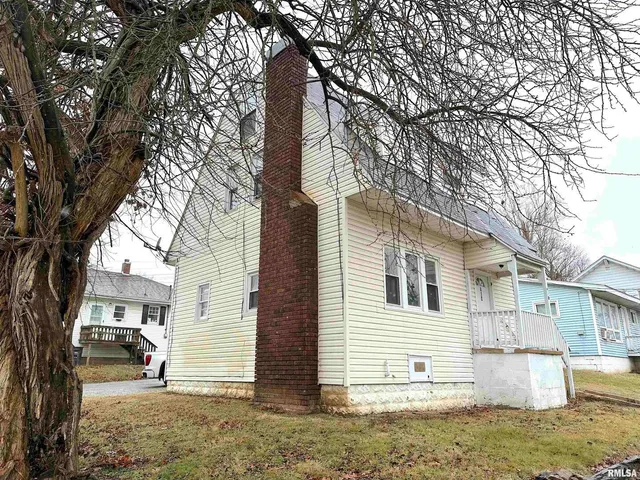 a view of a white house next to a road with big trees