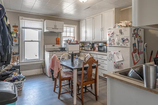 a kitchen with stainless steel appliances granite countertop a dining table chairs refrigerator and sink