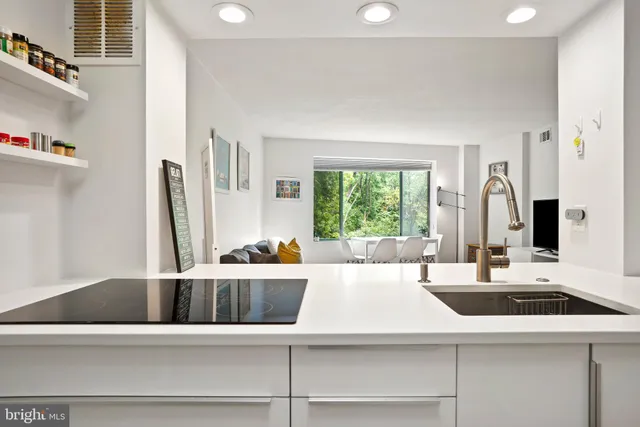 a hallway with white cabinets and refrigerator