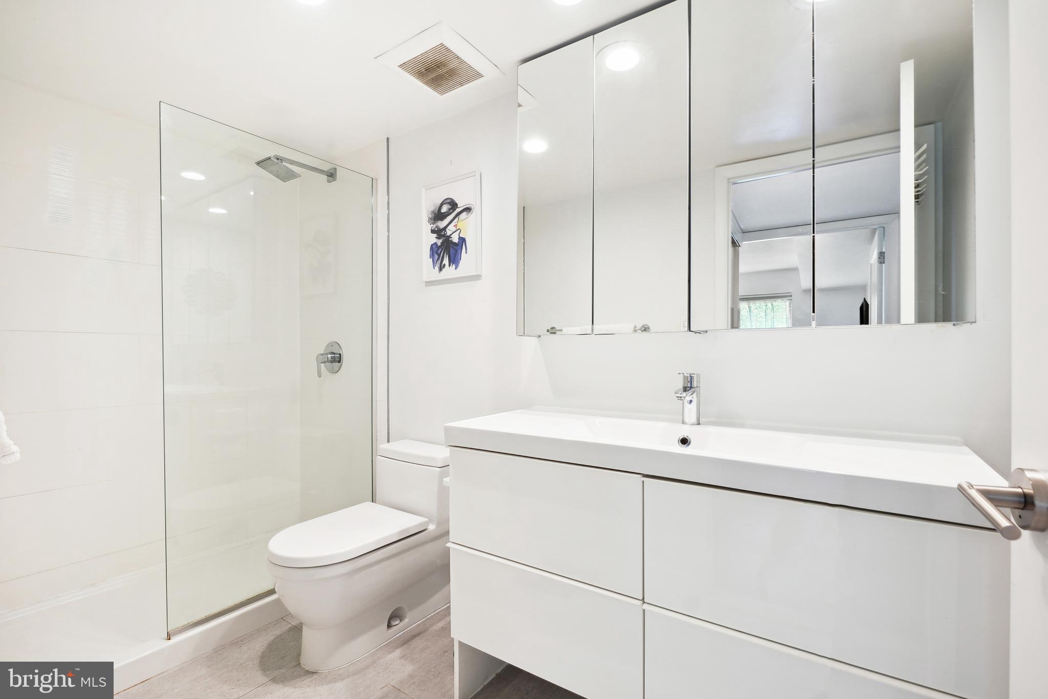 2141 Wisconsin Avenue Northwest, Unit 103 Washington, DC 20007 - Photo 21 of 30 a bathroom with a toilet sink vanity and mirror