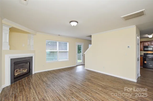 an empty room with wooden floor a fireplace and windows