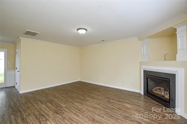 a view of an empty room with wooden floor and a fireplace