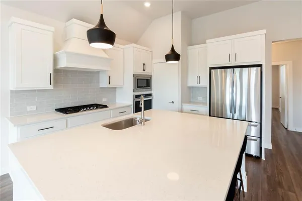 a kitchen with stainless steel appliances a refrigerator and a wooden floor