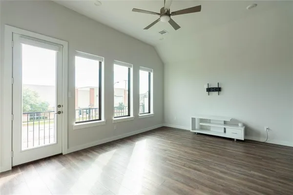 a view of an empty room with a window and wooden floor