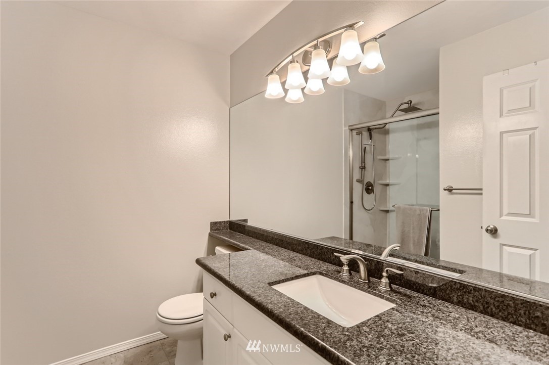 13400 Dumas Road, Unit E3 Mill Creek, WA 98012 - Photo 18 of 28 a bathroom with a granite countertop sink a toilet and a mirror