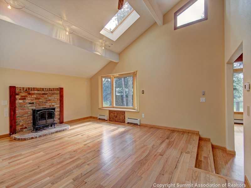 224 Spruce Creek Road Breckenridge, CO 80424 - Photo 9 of 21 an empty room with windows fireplace and wooden floor