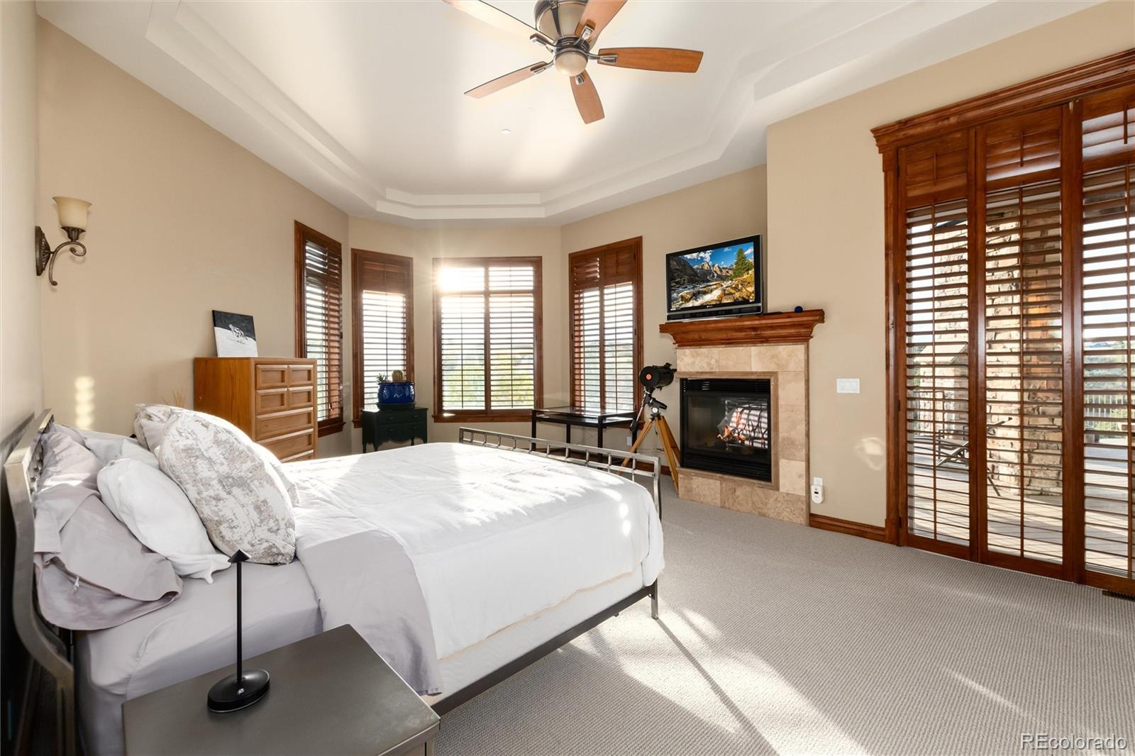 13079 Whisper Canyon Road Castle Pines, CO 80108 - Photo 26 of 50 a spacious bedroom with a bed and a fireplace