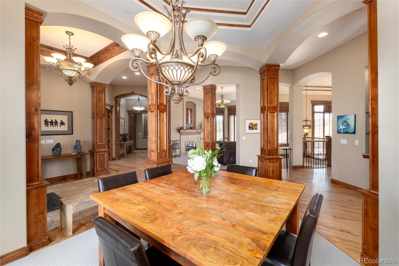 13079 Whisper Canyon Road Castle Pines, CO 80108 - Photo 10 of 50 a dining room with wooden floor a chandelier a wooden table and chairs