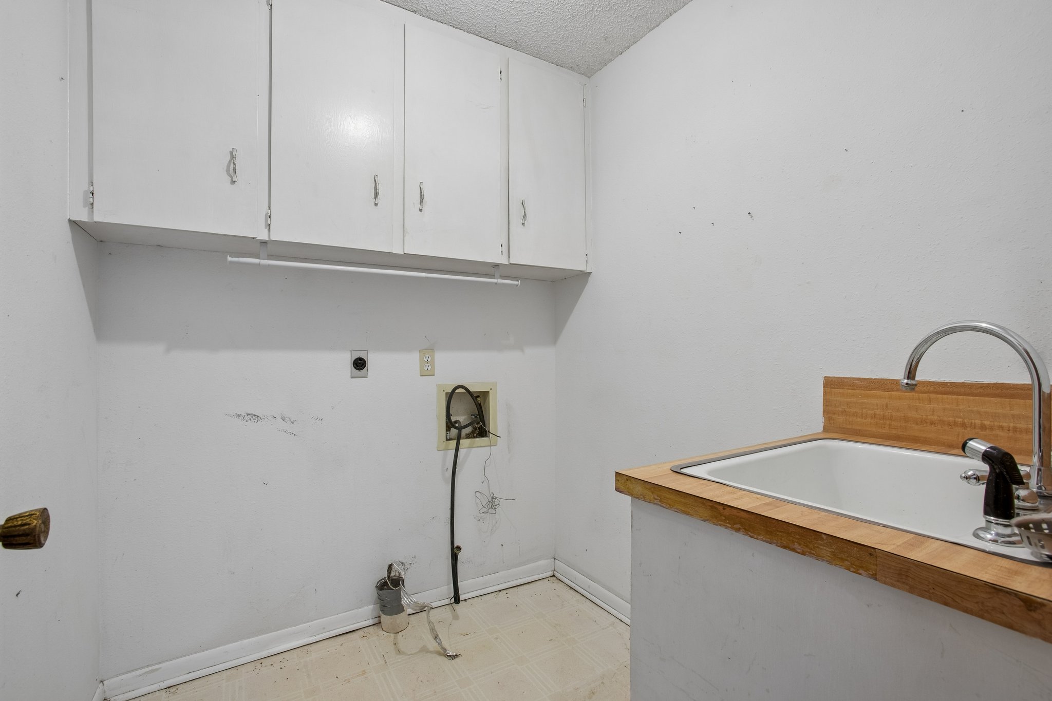 406 Monkey Road Elgin, TX 78621 - Photo 12 of 39 Utility room with overhead cabinetry, wood-finish countertop, and a built-in basin sink with a chrome faucet