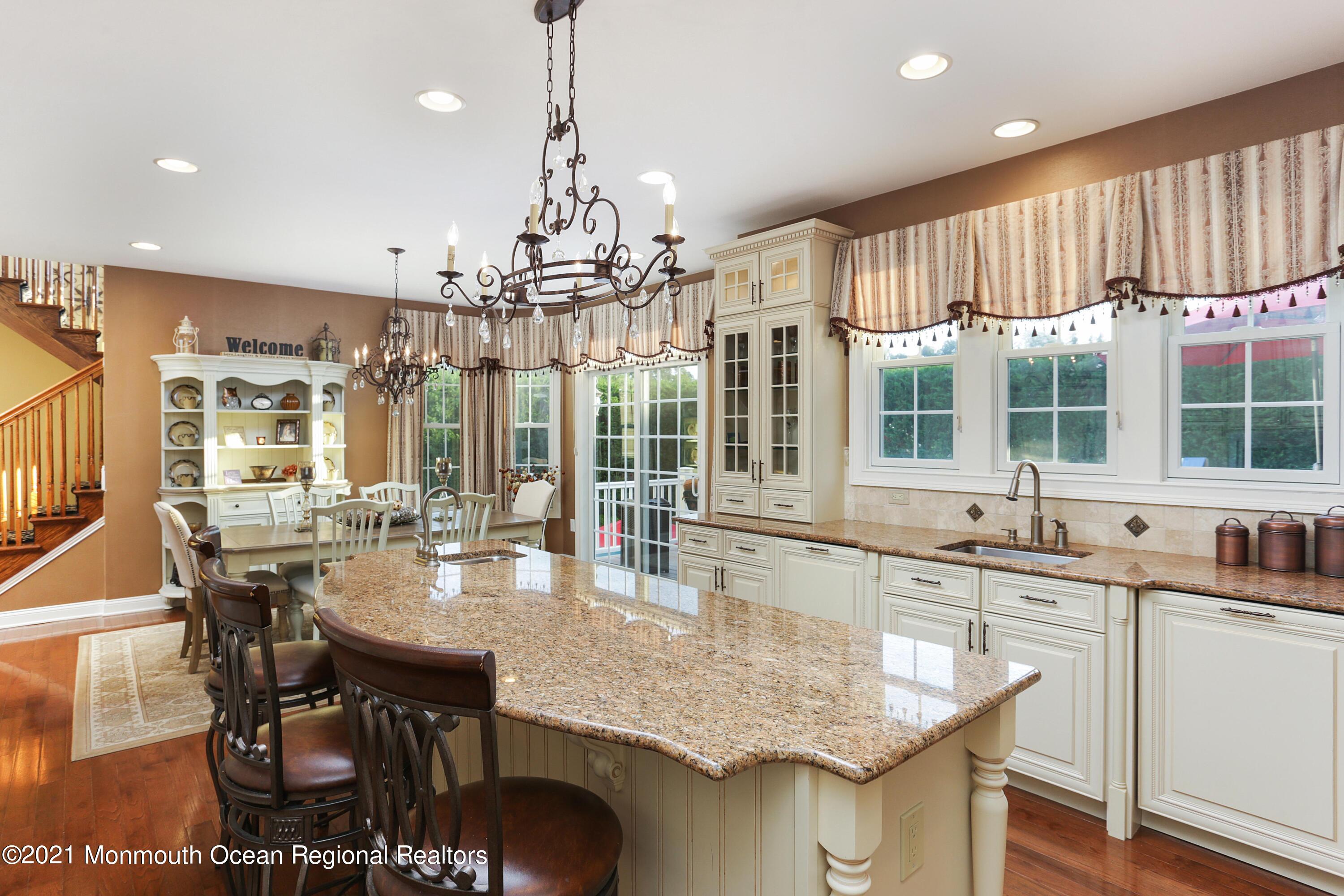 4 Yorktown Road Morganville, NJ 07751 - Photo 21 of 64 a kitchen with granite countertop a stove a sink a dining table and chairs with wooden floor