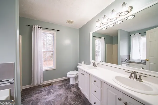 a spacious bathroom with a double vanity sink a mirror and a toilet