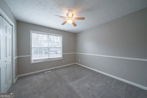 an empty room with windows and chandelier fan