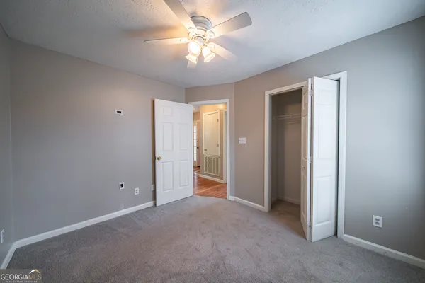 an empty room with closet and a ceiling fan