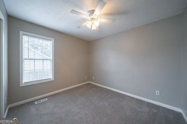 an empty room with windows and fan