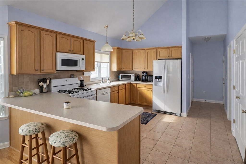 9 Arbor Road, Unit 9 Dracut, MA 01826 - Photo 6 of 27 a kitchen with a refrigerator a microwave a stove and cabinets