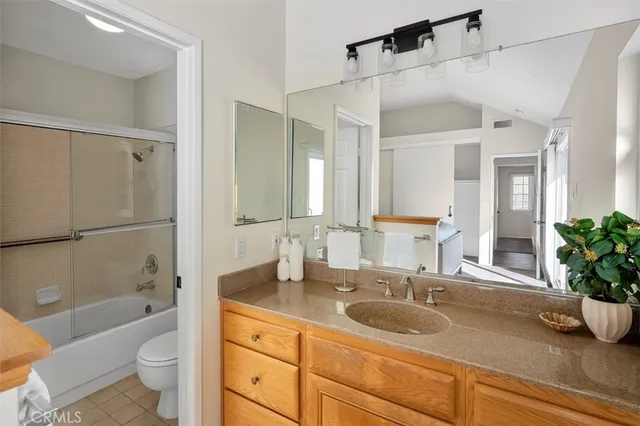 a bathroom with a granite countertop sink a toilet a mirror a vanity a shower and bathtub