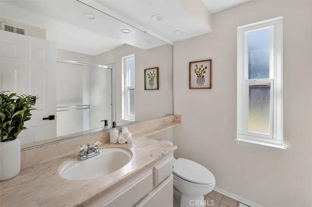 a bathroom with a granite countertop toilet a sink and a mirror