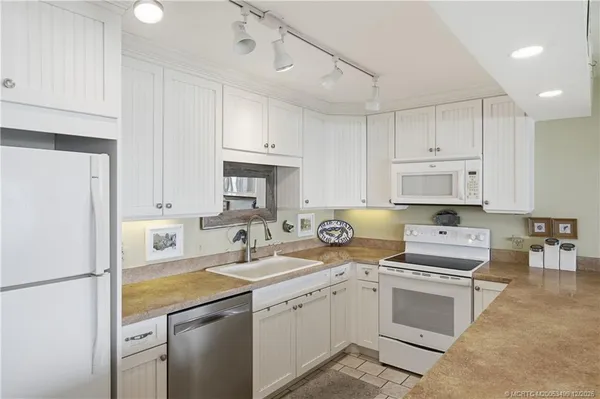 a kitchen with a sink a counter top space stainless steel appliances and cabinets