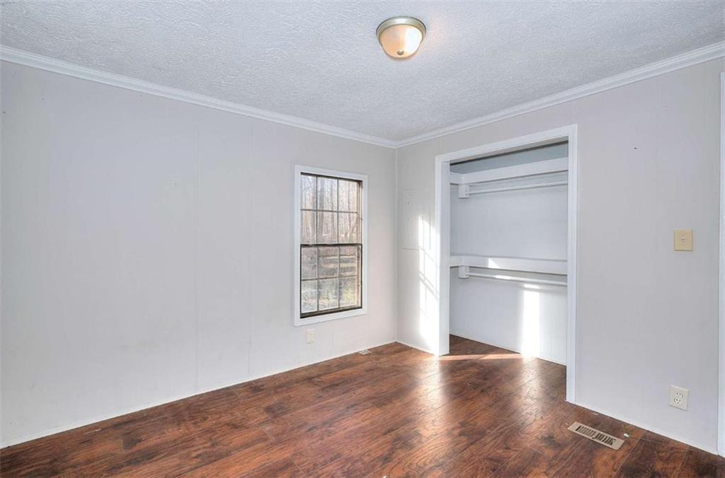 1210 Lee Peters Road Loganville, GA 30052 - Photo 24 of 32 an empty room with wooden floor cabinet and windows