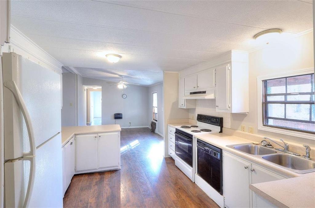 1210 Lee Peters Road Loganville, GA 30052 - Photo 9 of 32 a kitchen with stainless steel appliances granite countertop a sink stove and wooden floor