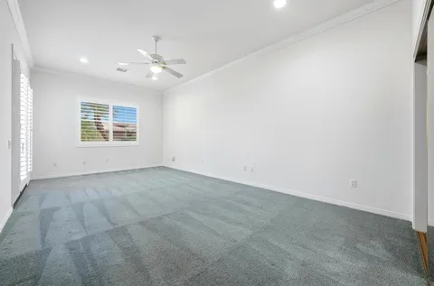 an empty room with windows and ceiling fan