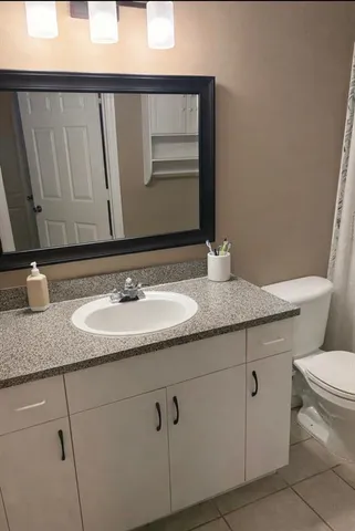 a bathroom with a granite countertop sink and a toilet
