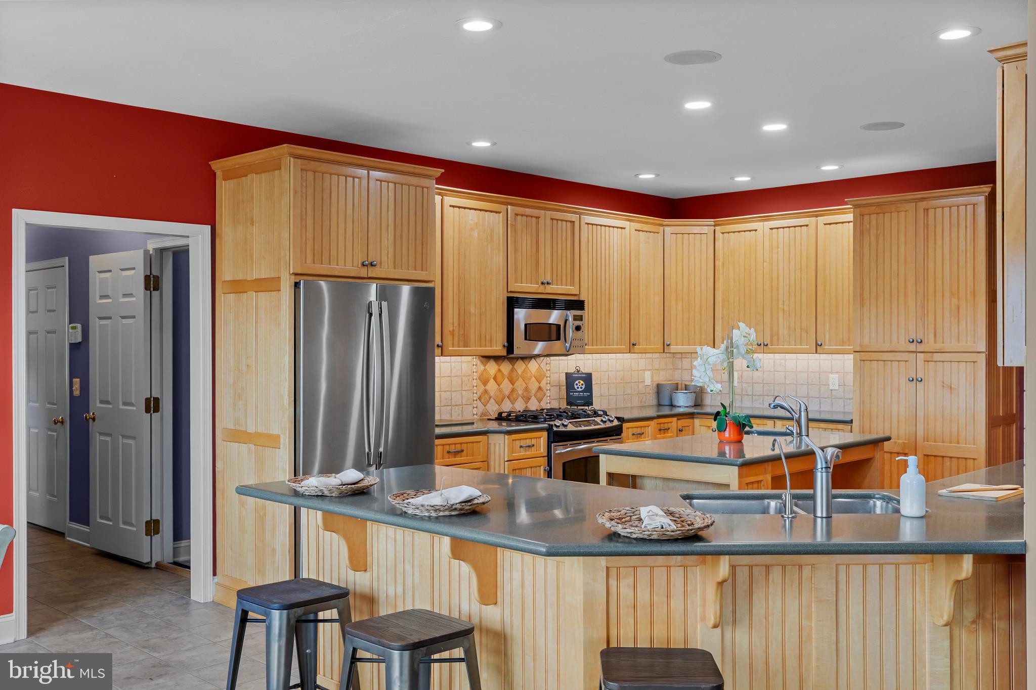 3239 Dry Branch Road White Hall, MD 21161 - Photo 20 of 56 a kitchen with stainless steel appliances granite countertop a refrigerator a stove and a sink with wooden cabinets