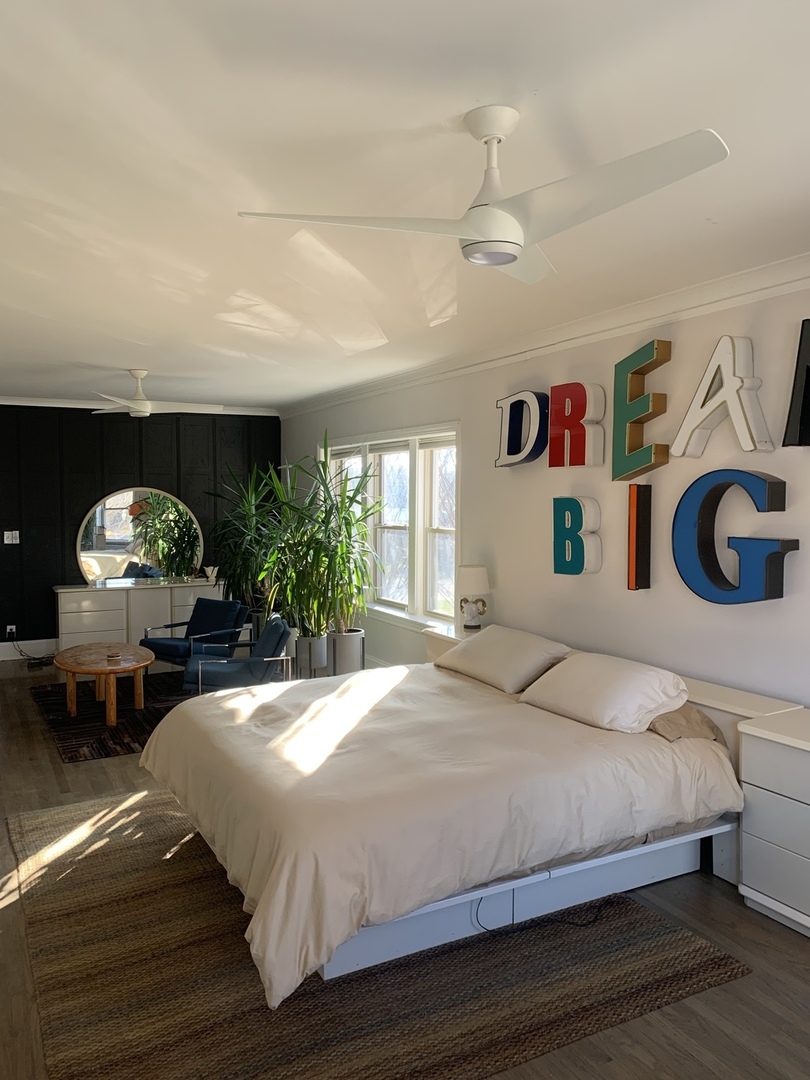 5259 West Roscoe Street, Unit 1F Chicago, IL 60641 - Photo 20 of 53 a bedroom with a bed a dresser and potted plants with wooden floor