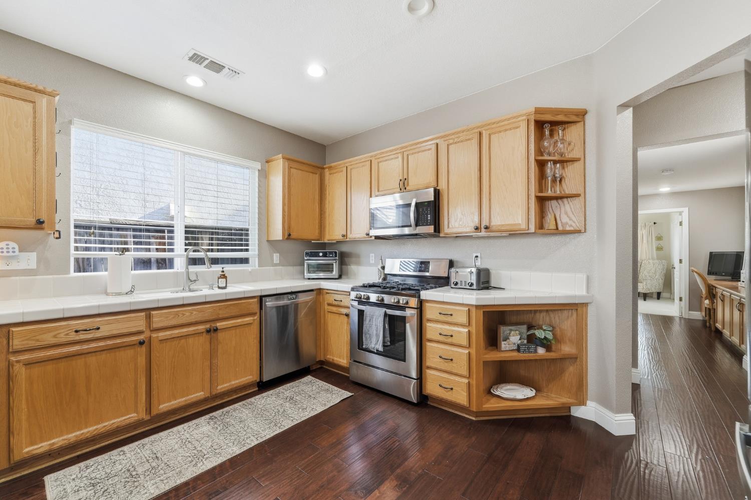 2220 Ellison Drive Modesto, CA 95355 - Photo 13 of 53 a kitchen with stainless steel appliances granite countertop wooden cabinets a stove a sink and a window