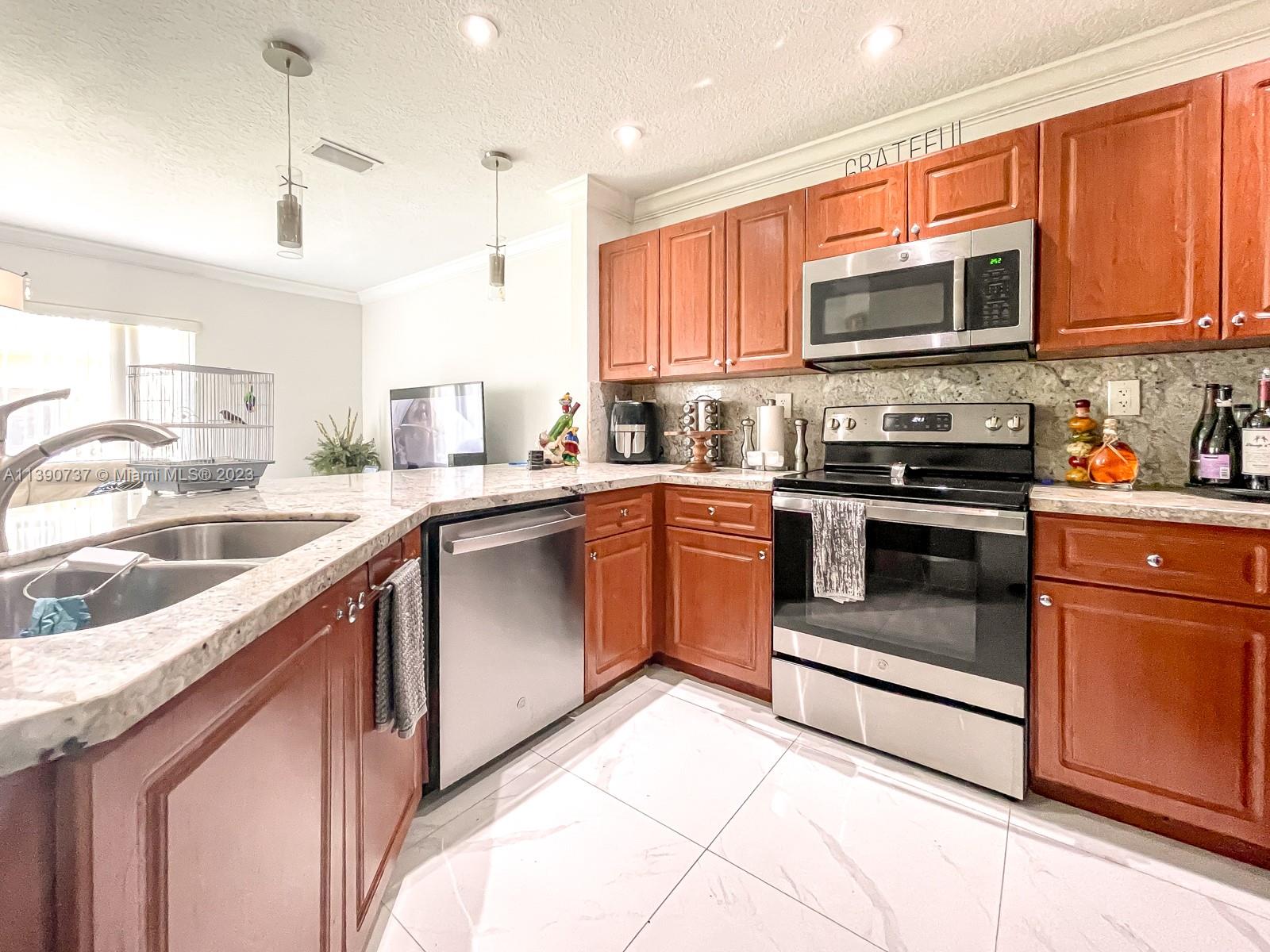 3136 Southwest 129th Way, Unit 157 Miramar, FL 33027 - Photo 8 of 23 a kitchen with stainless steel appliances granite countertop a sink a stove top oven and refrigerator