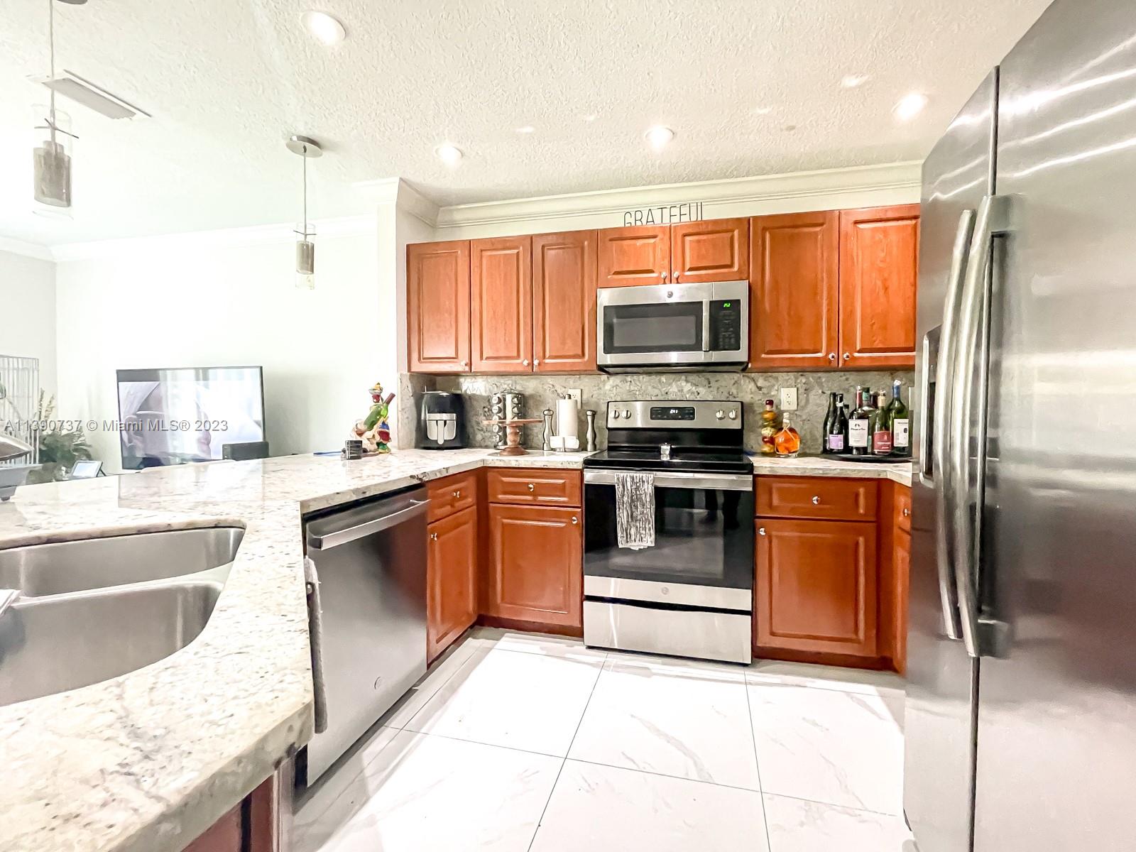 3136 Southwest 129th Way, Unit 157 Miramar, FL 33027 - Photo 9 of 23 a kitchen with stainless steel appliances granite countertop a refrigerator a stove a sink and a microwave