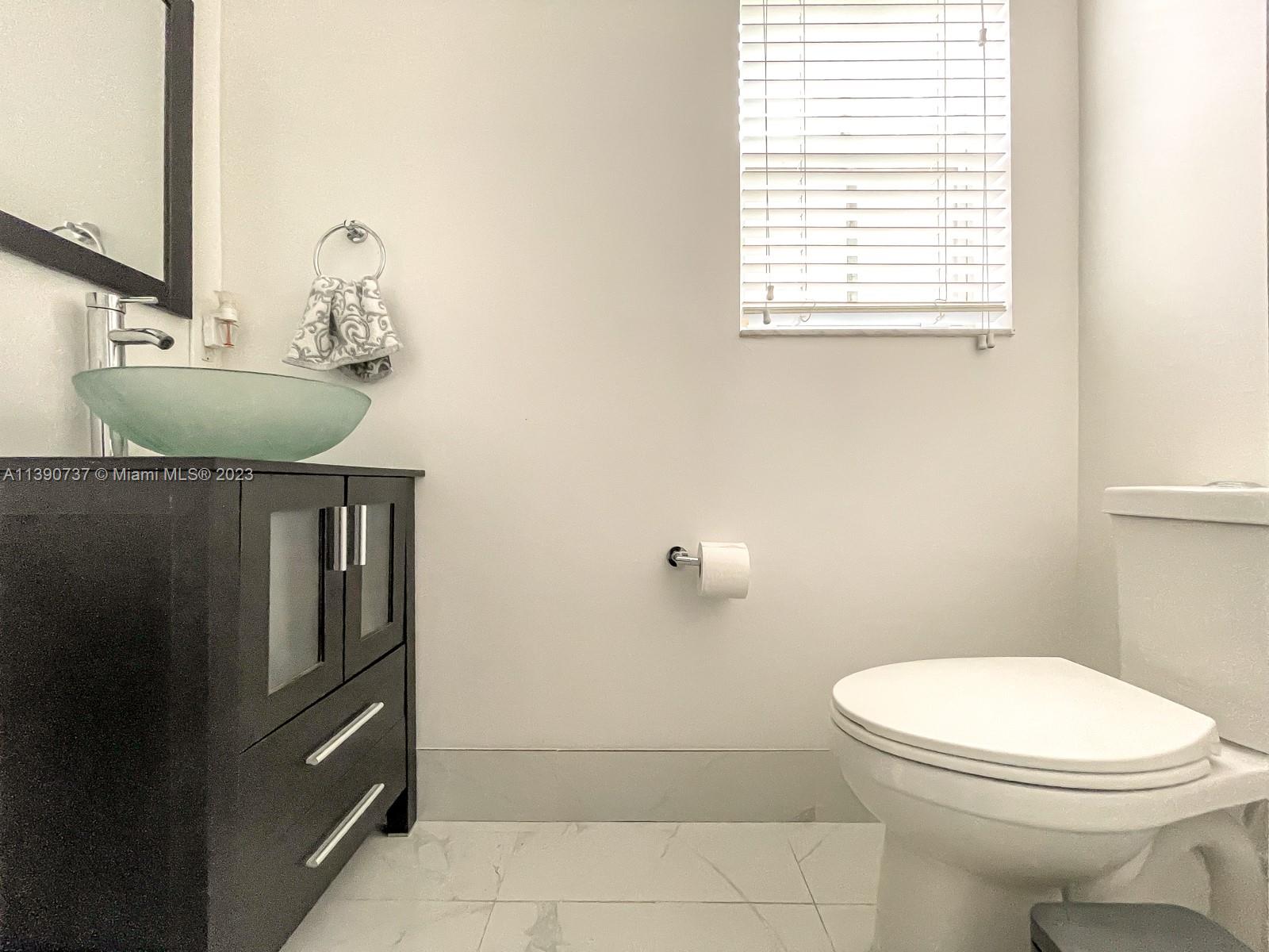 3136 Southwest 129th Way, Unit 157 Miramar, FL 33027 - Photo 10 of 23 a bathroom with a toilet sink and mirror