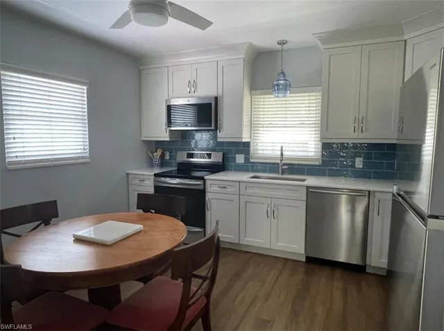 a kitchen with stainless steel appliances granite countertop a kitchen island hardwood floor sink stove dining table and chairs