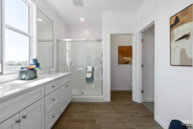 a spacious bathroom with a double vanity sink a large mirror a shower and a bathtub