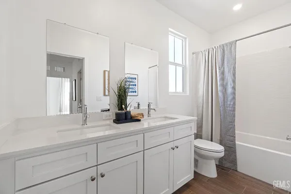 a bathroom with a granite countertop sink toilet a large mirror a bathtub and next to a window
