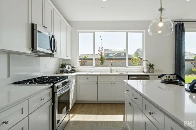 a kitchen with stainless steel appliances granite countertop a sink a stove and cabinets