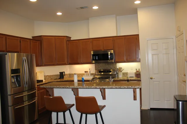 a kitchen with stainless steel appliances granite countertop a refrigerator a stove a sink and a microwave