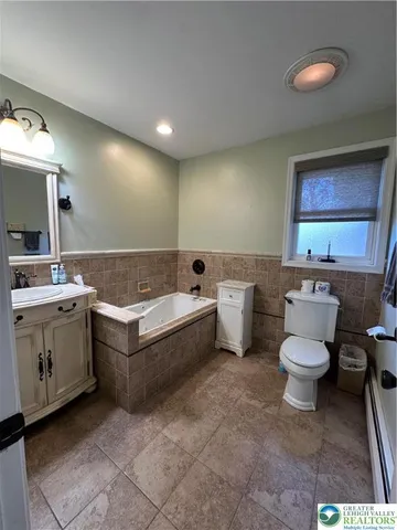 a bathroom with a bathtub sink mirror vanity and toilet