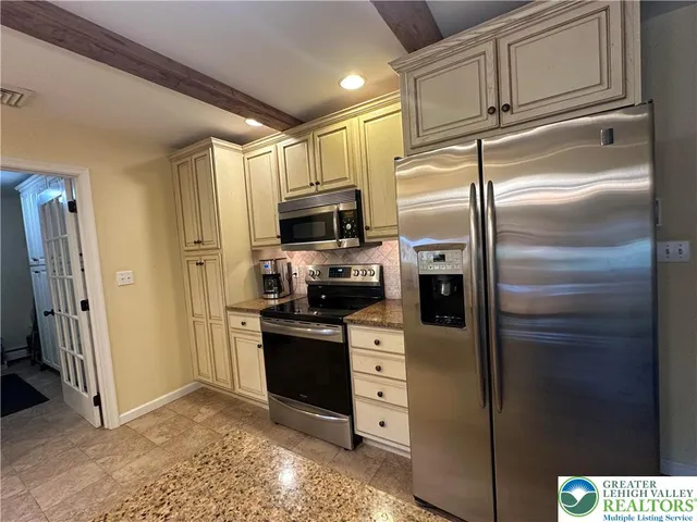 a kitchen with stainless steel appliances granite countertop a refrigerator a stove and a sink