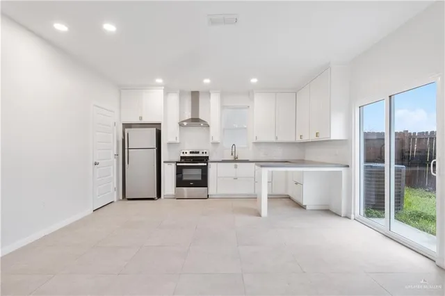 a view of kitchen with refrigerator and white cabinets