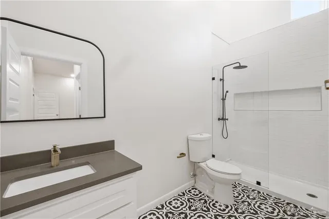 a bathroom with a granite countertop sink mirror vanity and toilet