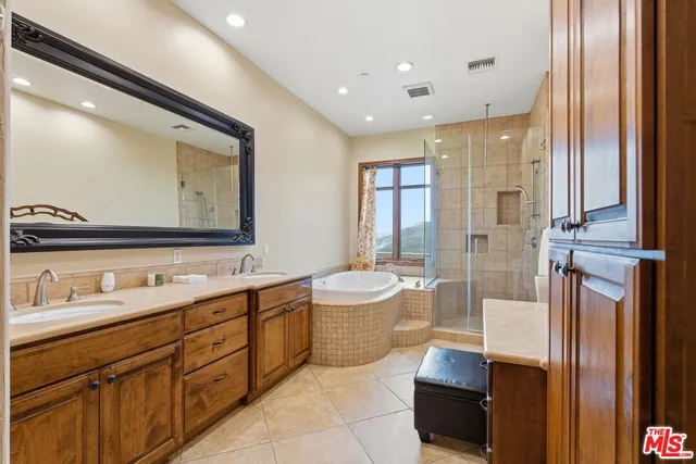 a spacious bathroom with a double vanity sink a toilet a mirror and a shower