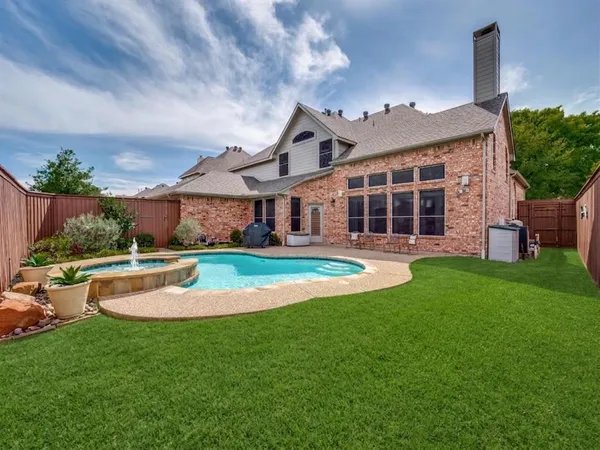 a view of a house with a big yard potted plants and large tree