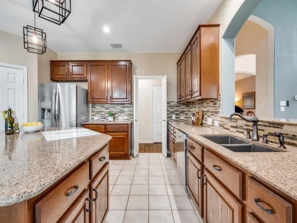 a kitchen with stainless steel appliances granite countertop a sink a stove and a wooden cabinets