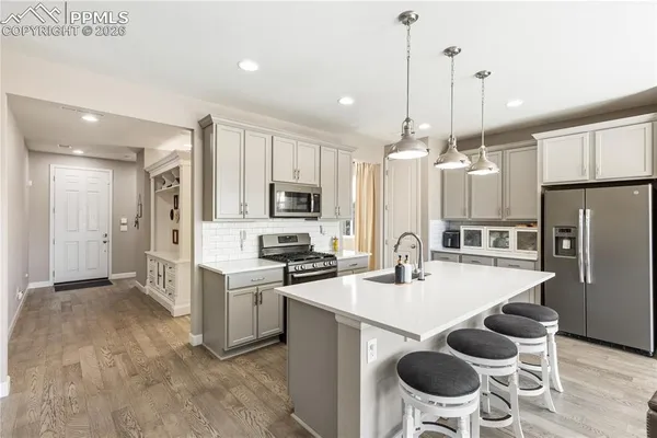a kitchen with stainless steel appliances kitchen island granite countertop a sink a stove a refrigerator cabinets and chairs